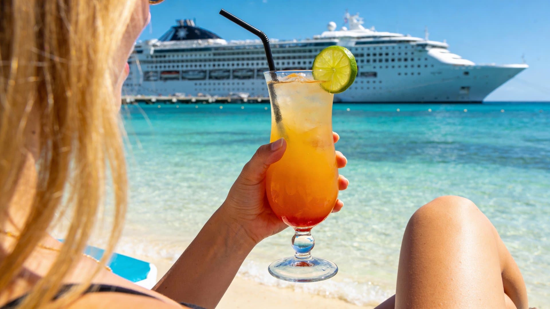 Colorful tropical cocktail with umbrella on cruise ship deck overlooking ocean wake