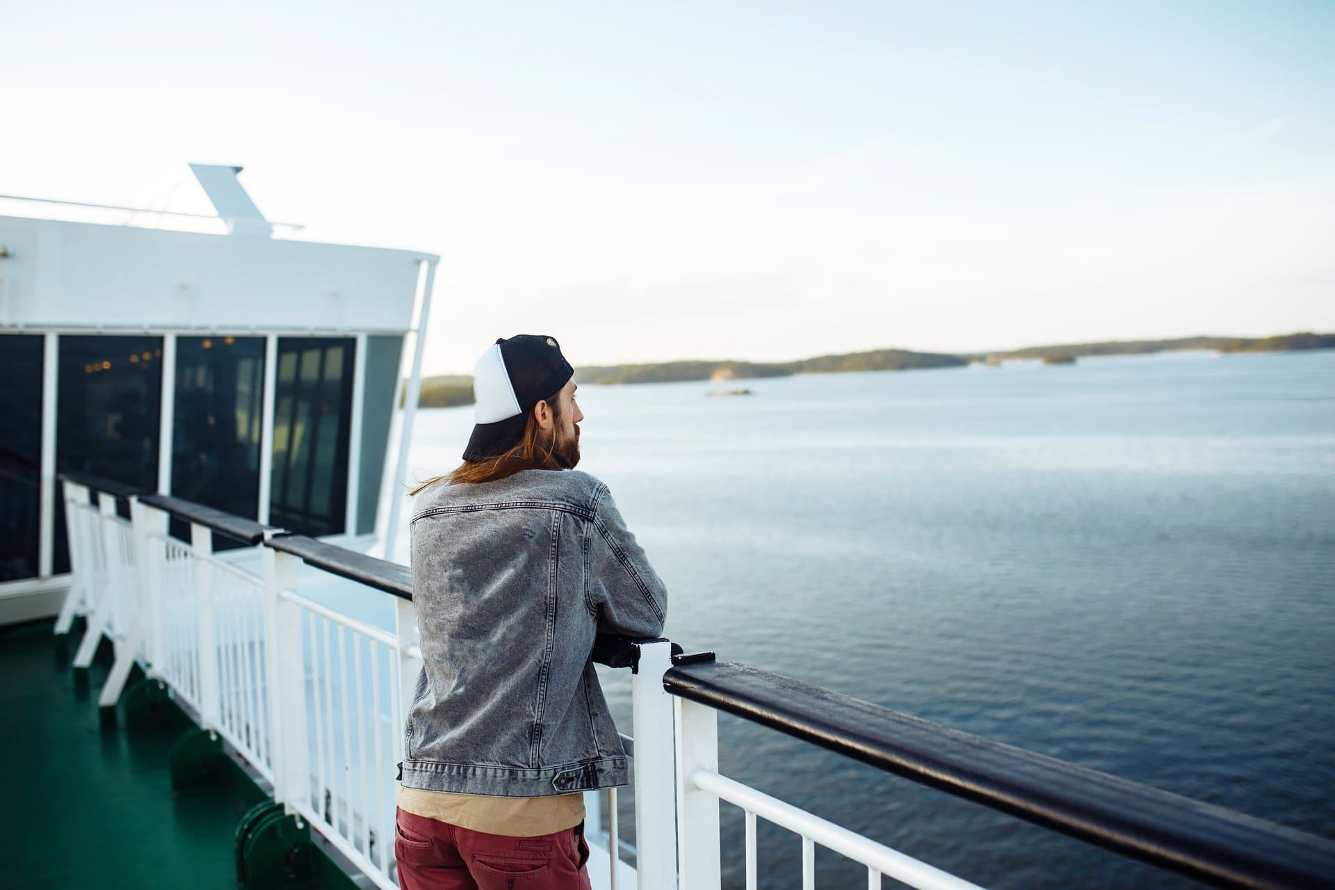 A woman in a hat and shorts standing on the balcony of a cruise ship,.